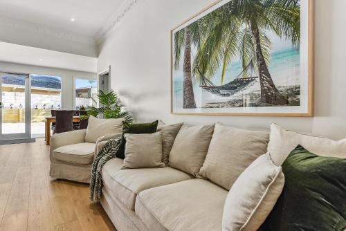 a living room with a couch and palm trees at Robe Beach Stays in Robe