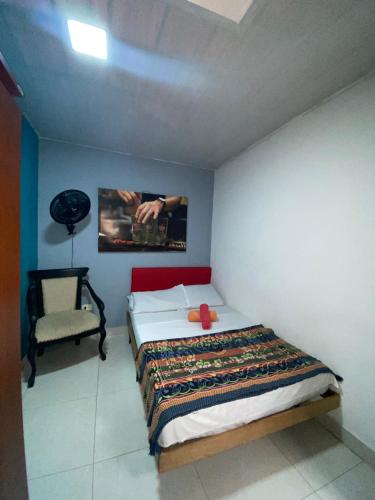 a small bedroom with a bed and a chair at Havana Dance School & Hostel in Cali