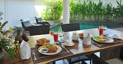 a wooden table with plates of food on it at Villa La Sirena by Nagisa Bali in Seminyak