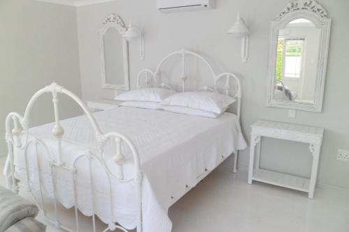a white bedroom with a white bed and two mirrors at Kastelein Guesthouse in Pongola