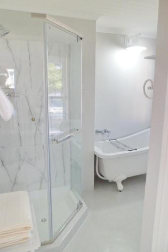 a white bathroom with a shower and a sink at Kastelein Guesthouse in Pongola