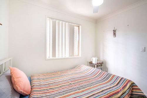 a bedroom with a bed with a striped blanket at Private Room with Separate Bath in Shared Accommodation in Redcliffe