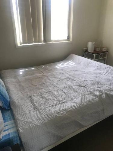 a white bed in a bedroom with a window at Private Room in Shared Accommodation in Redcliffe
