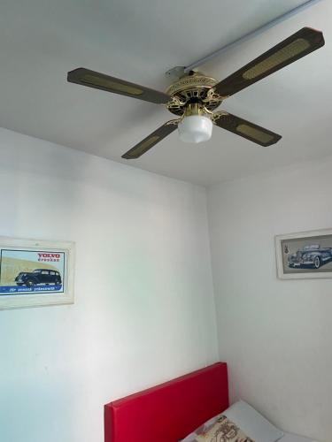a ceiling fan in a room with a red bed at Havana Dance School & Hostel in Cali