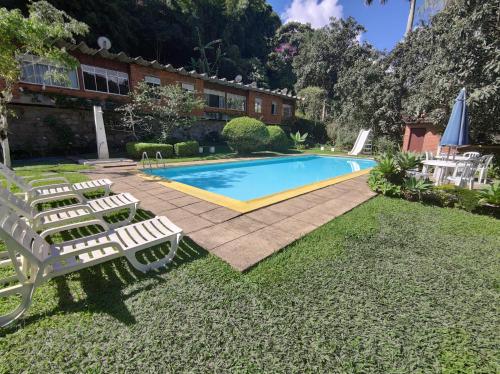 a swimming pool with two chairs next to a house at Terê c/Lazer completo-RelaxTerêMontainHouse in Teresópolis