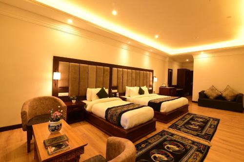 a hotel room with two beds and a couch at Hotel Barath Ladakh in Leh
