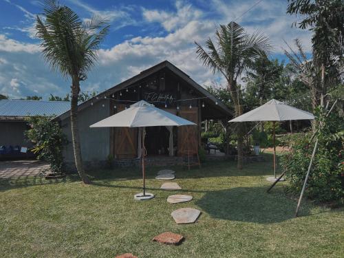 two umbrellas in the grass in front of a building at Mộc An Nhiên Farmstay in Pleiku