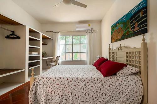 sypialnia z łóżkiem z czerwonymi poduszkami i oknem w obiekcie JUNTO AL MAR Y EL MANGLAR w mieście Cartagena de Indias