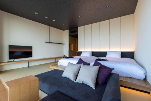 a bedroom with a bed and a couch and a tv at The358 SORA in Fukuoka