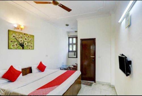 a bedroom with a bed with red pillows and a tv at OYO Chaudhry Hotel in Hāthras