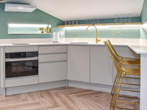 a kitchen with white cabinets and a sink and a chair at Barn Owls Nest-uk39432 in Dronfield