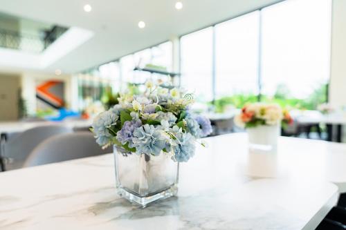 Fresh Resort Pattaya في Ban Huai Yai: مزهرية مليئة بالورود تجلس على طاولة