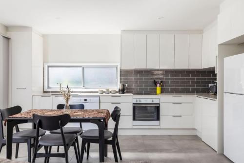 a kitchen with white cabinets and a table and chairs at Taylors Beach Cottage in Taylors Beach