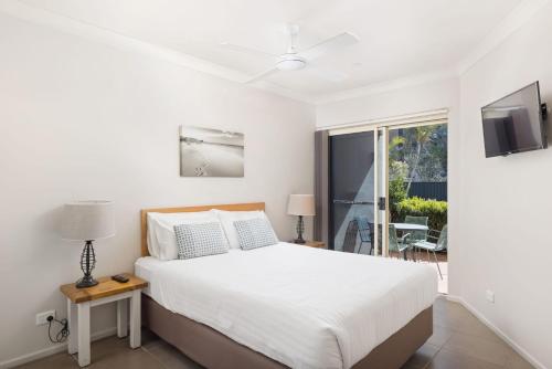 a bedroom with a white bed and a balcony at Martys No 5 in Nelson Bay