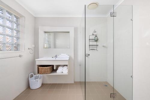 a white bathroom with a sink and a shower at Martys No 5 in Nelson Bay