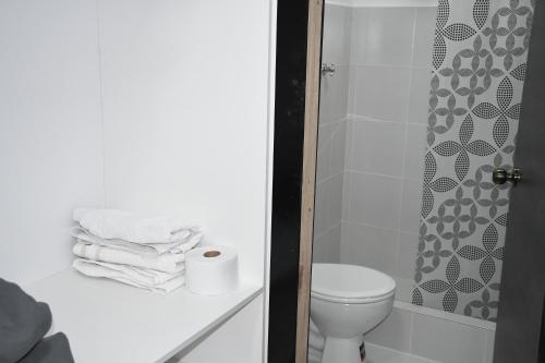 a bathroom with a toilet and a shower with towels at Mini Suites Cuarto Piso Alkimya in Loja
