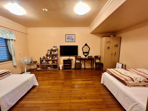 a living room with two beds and a flat screen tv at Sin Ya Homestay in Sanyi