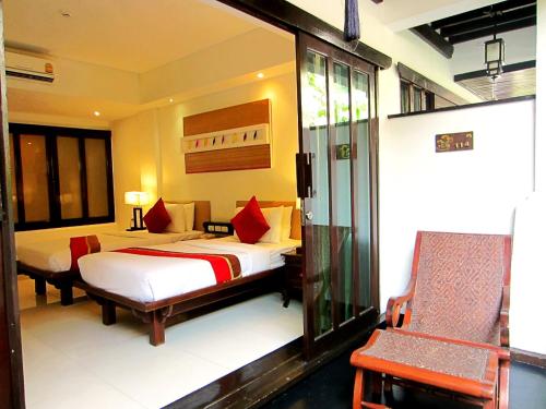 a hotel room with two beds and a chair at Yantarasri Resort in Chiang Mai