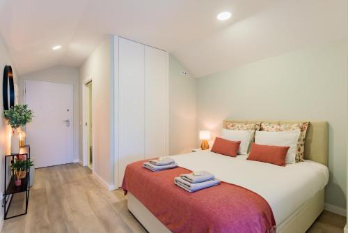 アヴェイロにあるTeatro à Vista - No coração do centro de Aveiroのタオルが敷かれた大きな白いベッドのある寝室