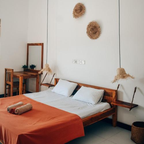 a bedroom with a bed with orange sheets and a mirror at Salty Alchemy in Arugam Bay
