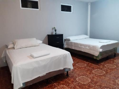 2 camas en una habitación con sábanas blancas en Casa Elenita, en San Juan La Laguna