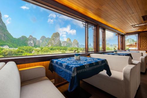 a room with a table and chairs and mountains in the background at Li River Gallery Lodge in Yangshuo