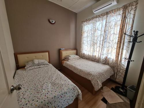 two beds in a small room with a window at Al-Bayt Homestay in Ayer Keroh
