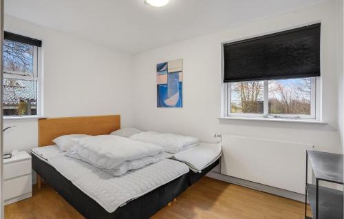 1 Schlafzimmer mit einem Bett mit weißer Bettwäsche und 2 Fenstern in der Unterkunft Beautiful Home In Ebeltoft With 5 Bedrooms, Sauna And Wifi in Ebeltoft