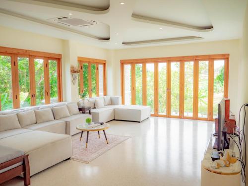 a large living room with white furniture and windows at Nichahome Luxury Villa in Hua Hin