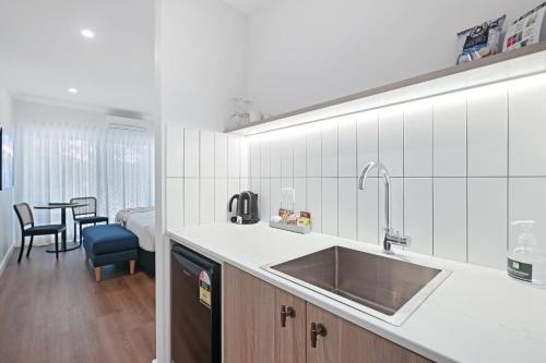a kitchen with a sink and a room with a bed at Clare Country Club in Clare