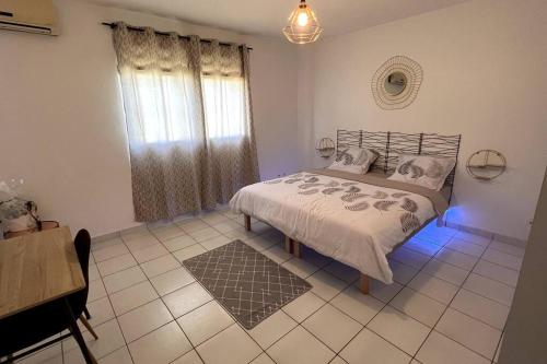 1 dormitorio con cama, ventana y alfombra en Appartement T3 spacieux, en Montjoly