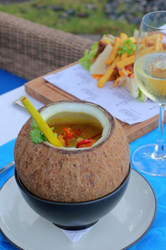 a bowl of soup on a table with a glass of wine at Sagara Candidasa by AHM in Candidasa