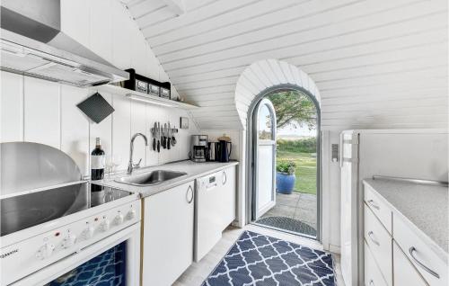 a kitchen with white cabinets and a sink and an archway at Hobbit Huset in Ringkøbing