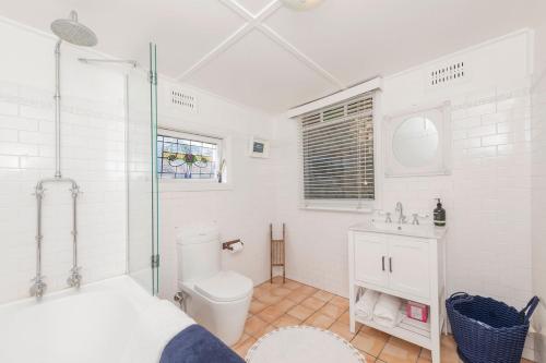 a white bathroom with a toilet and a sink at Selby Cottage - Intimate Waterfront Getaway in Marks Point