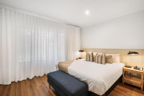 a bedroom with a white bed and a large window at Clare Country Club in Clare