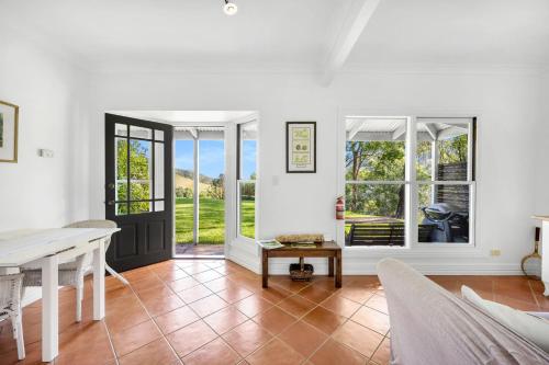 an open living room with a table and windows at Watta Cottage in Wattamolla