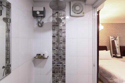 a bathroom with a shower and a bed in a room at Sweetloft Hotel Don Muang in Bangkok