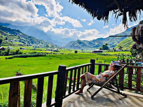 a woman sitting in a chair on a porch looking at a field at Sapa Eco Homestay in Sa Pa