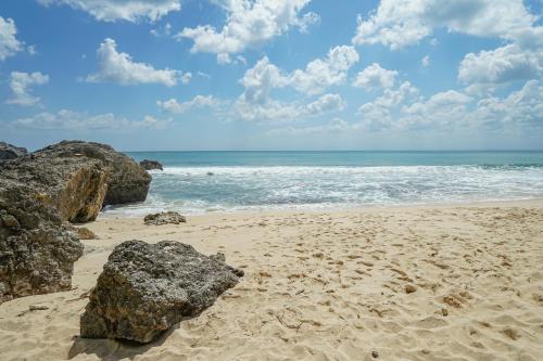 a sandy beach with some rocks and the ocean at Milo's Home in Jimbaran