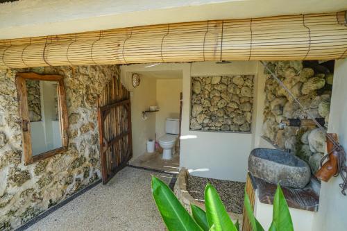 a bathroom with a toilet and a stone wall at Milo's Home in Jimbaran