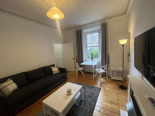 a living room with a black couch and a table at The Leith Walk Flat (just off) in Edinburgh