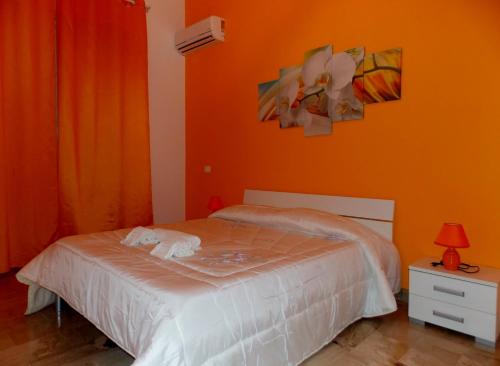a bedroom with a bed with an orange wall at Case Saniela in Terrasini