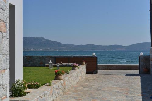 a retaining wall next to the water with flowers at Villa Aggemari in Apidias Lakos