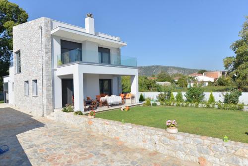 a large white house with a stone wall at Villa Aggemari in Apidias Lakos