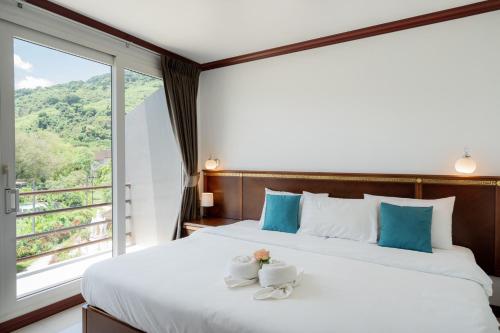 a bedroom with a bed with two cups and a window at Hotel De Karon in Karon Beach