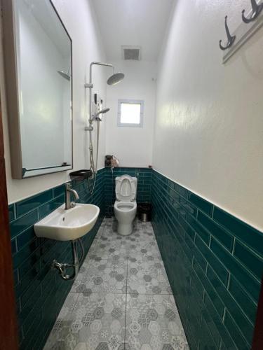 uma casa de banho com azulejos verdes, um WC e um lavatório. em ComeHome Lamphun em Lamphun
