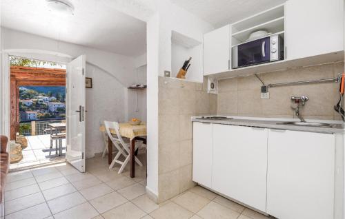 cocina con armarios blancos y vistas a una mesa en Amazing Home In Klada With House Sea View, en Donja Klada