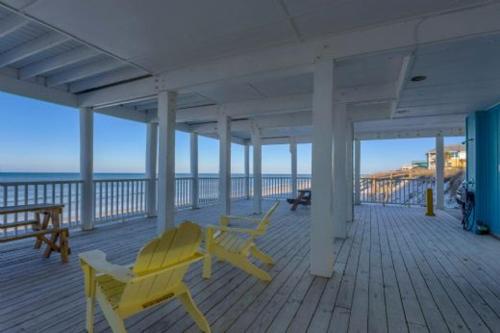 a deck with yellow chairs on a pier with the ocean at Pelican Crossing by Pristine Properties Vacation Rentals in Cape San Blas