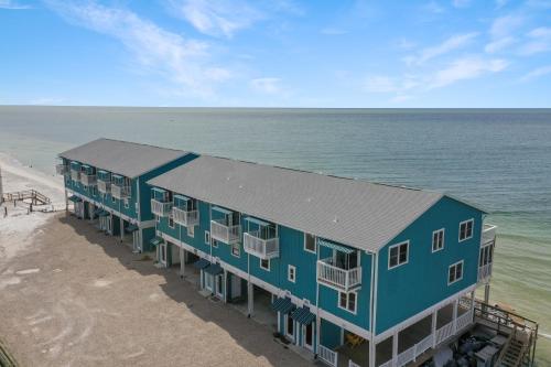 a blue building on the beach next to the ocean at Pelican Crossing by Pristine Properties Vacation Rentals in Cape San Blas