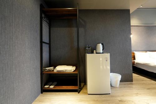 a white refrigerator in a room with a bed at Meworld Hotel - Songshan in Taipei